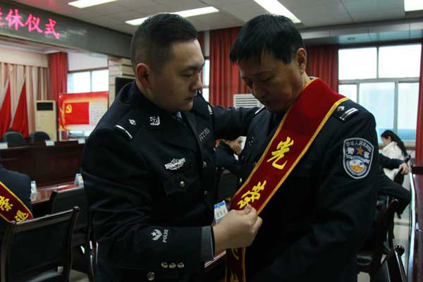 新警为退休民警整理绶带
